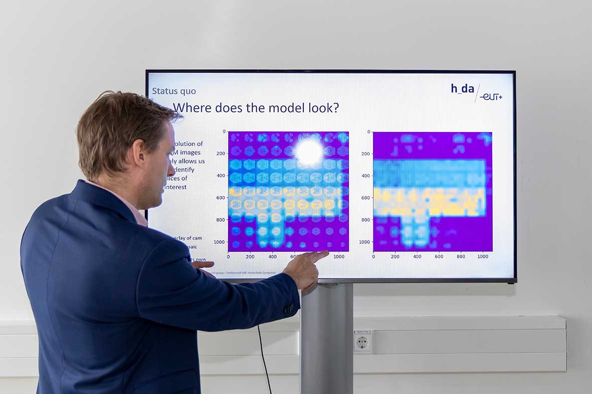 Prof. Gregori from the Department of Mathematics and Natural Sciences at Darmstadt University of Applied Sciences h_da in front of a large monitor with a series of brain scans.