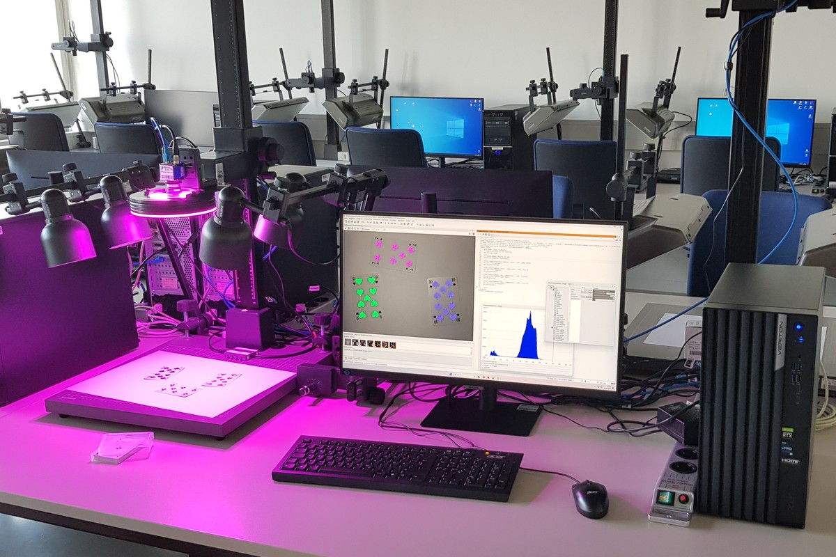 VDU workstation in the image processing lab: on the left you see a light source illuminating three playing cards. On the right you see a screen showing the illuminated playing cards incl. graph of the brightness distribution.